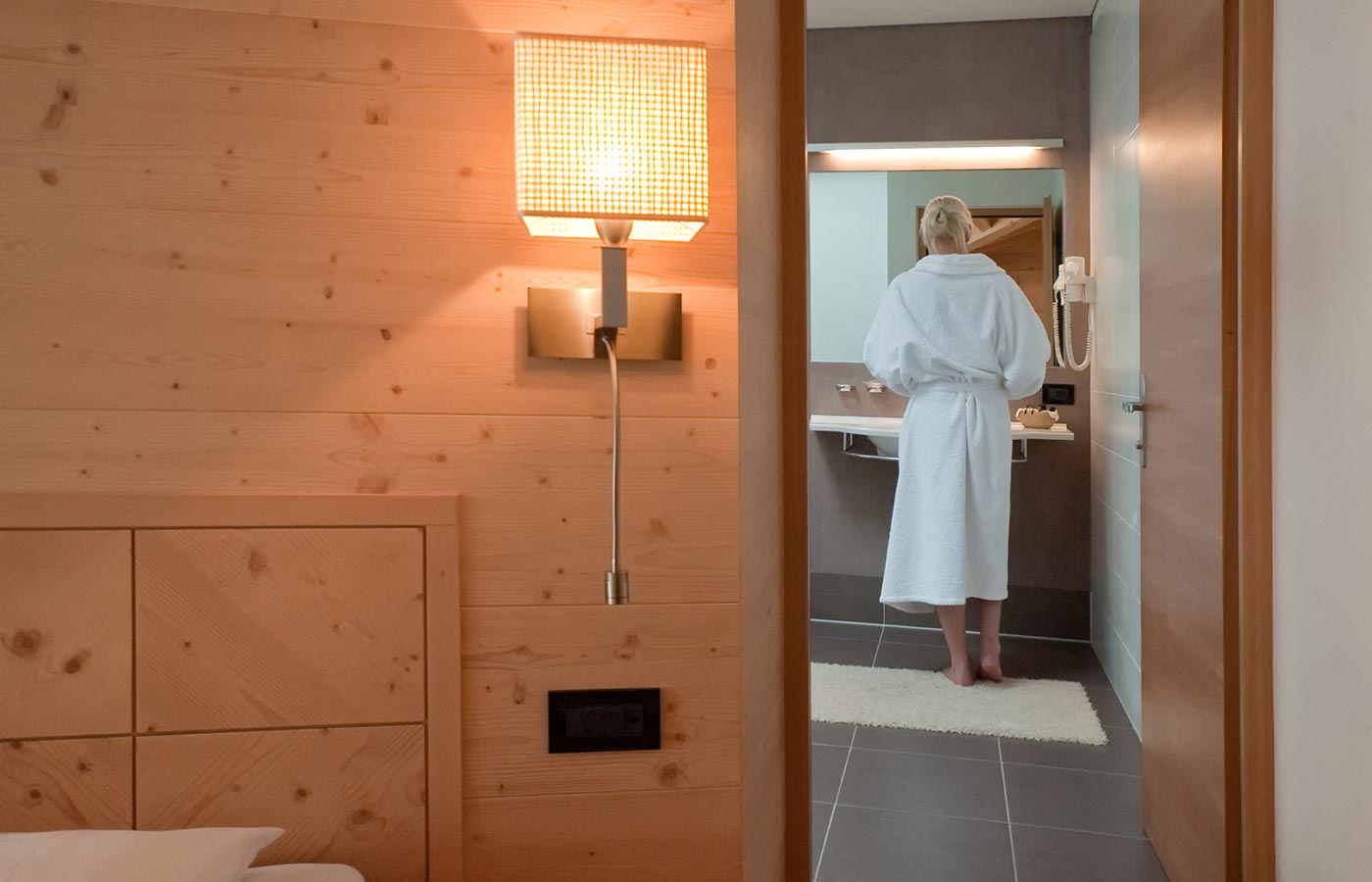 Eine Frau steht vor dem Spiegel im Badezimmer des Hotels Cavallino