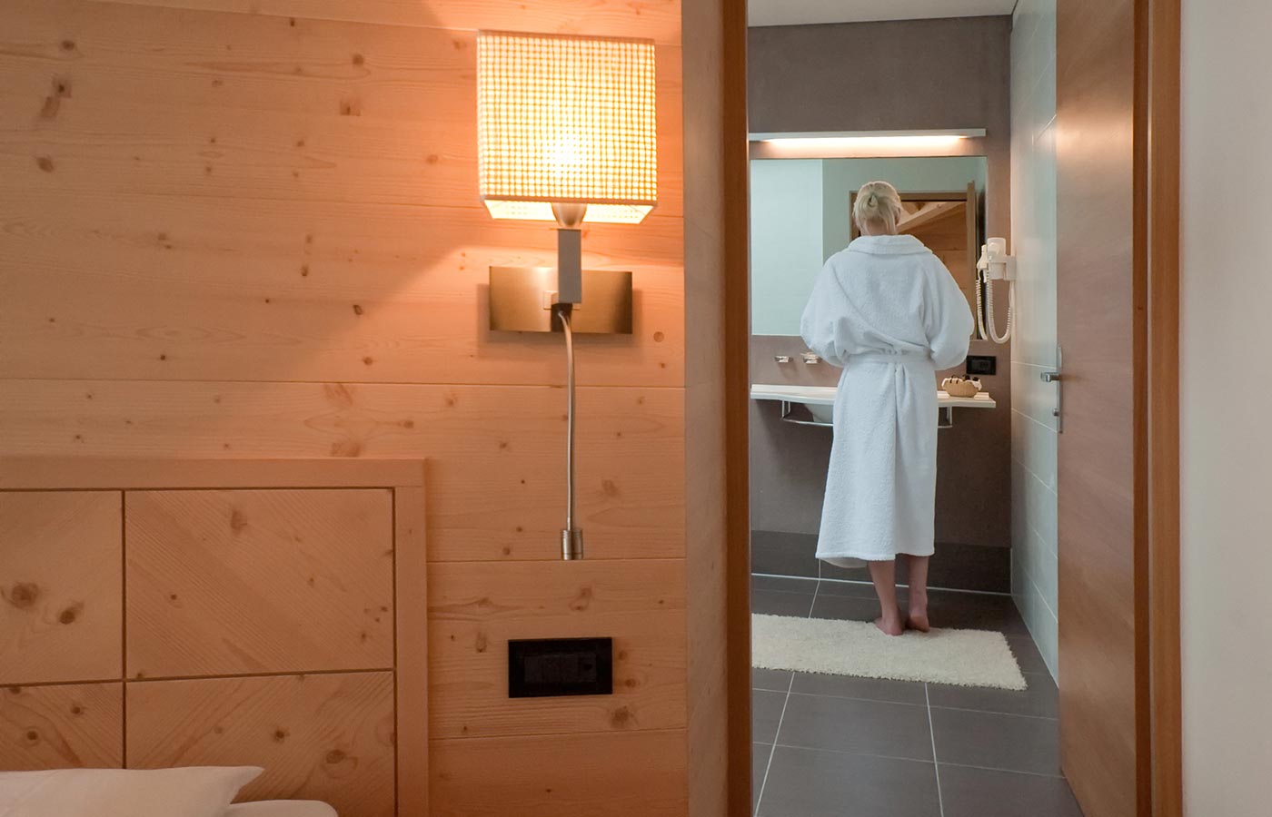 Woman in front of the mirror in the bathroom of Hotel Cavallino