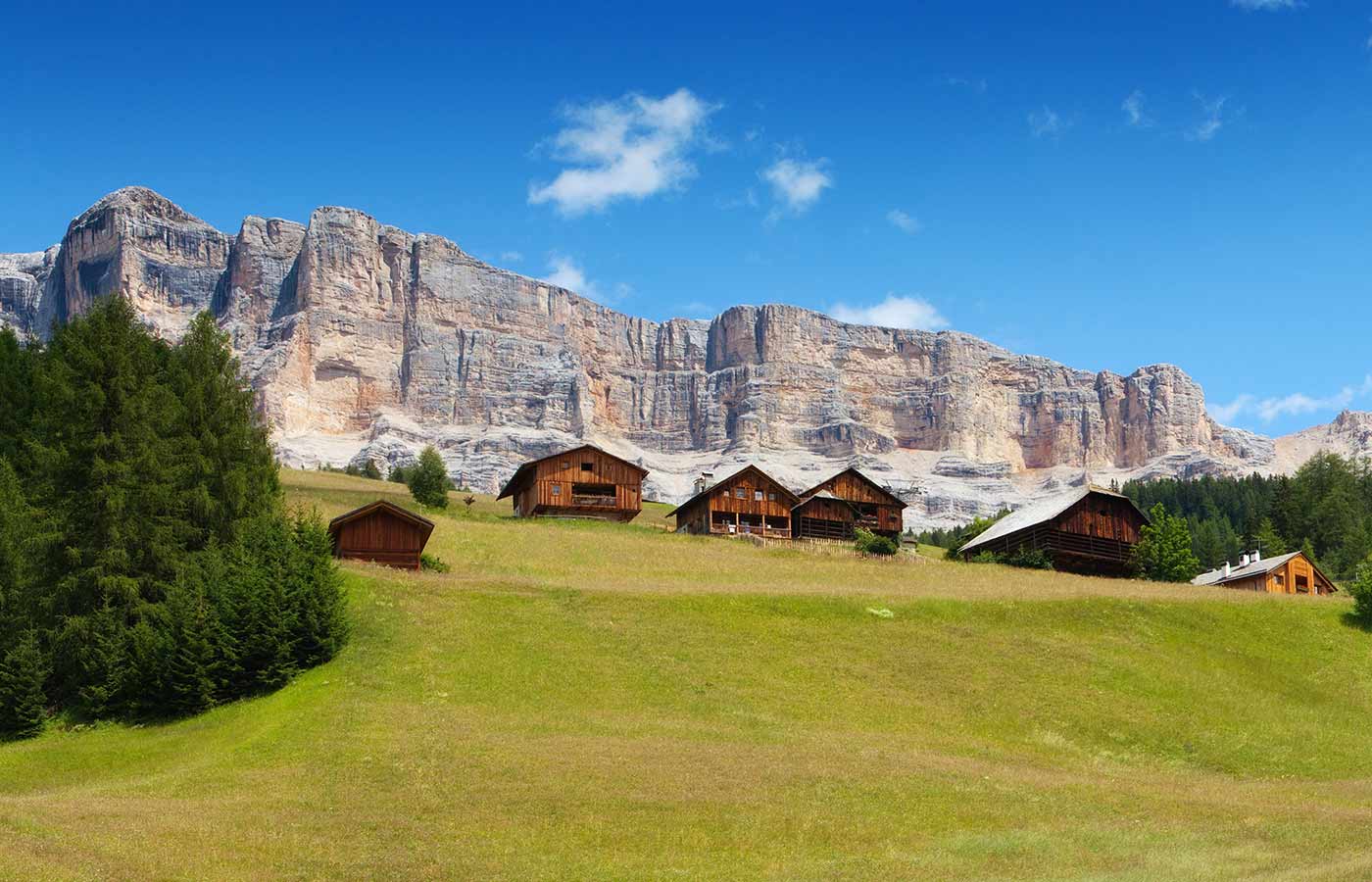 Wiesen mit Almhütten und Dolomiten im Hintergrund
