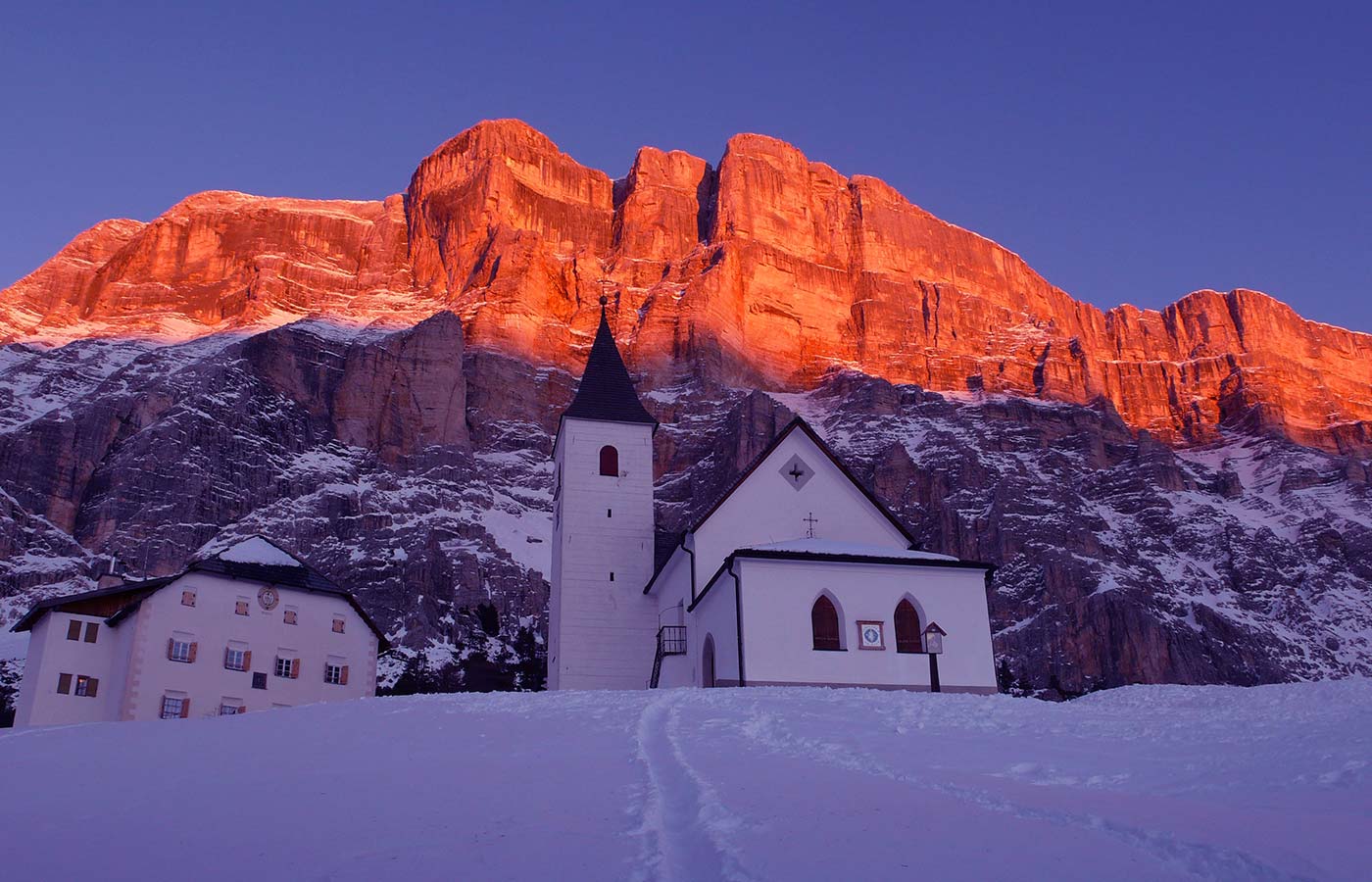 Una chiesetta innevata con uno spettacolare tramonto dolomitico